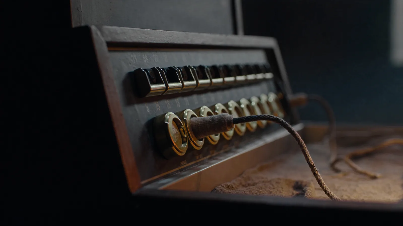 Klinkenfeld einer alten Telefonzentrale im Halbdunkel, ein Kabel gesteckt, warmes Licht auf dem Messing