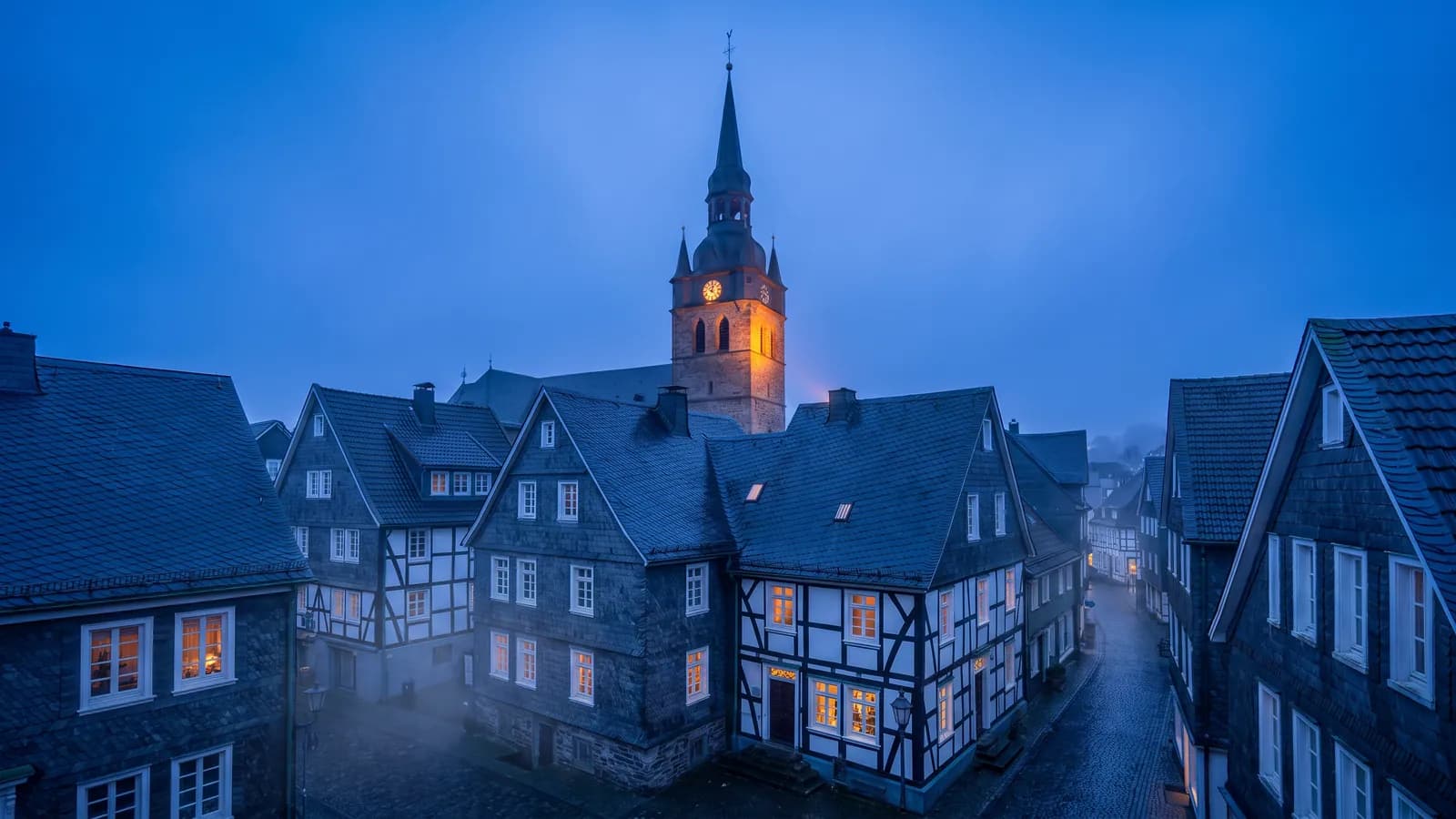 Rathausturm über schieferverkleideten bergischen Häusern zur blauen Stunde