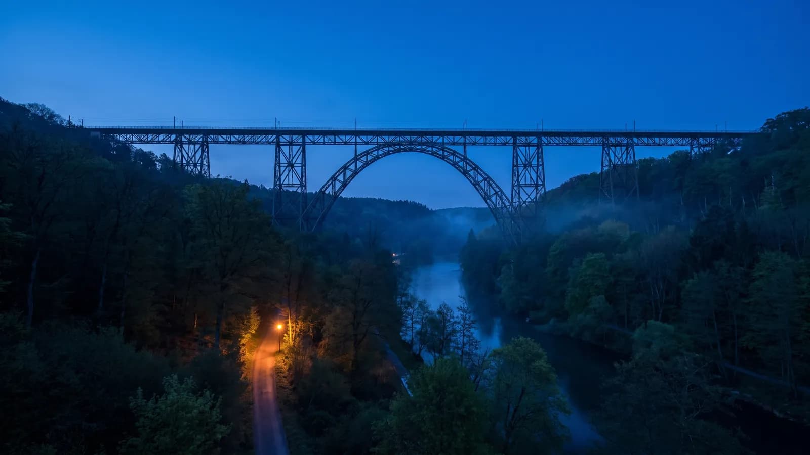 Müngstener Brücke, stählerne Bogenbrücke über dem bewaldeten Wuppertal in der Dämmerung